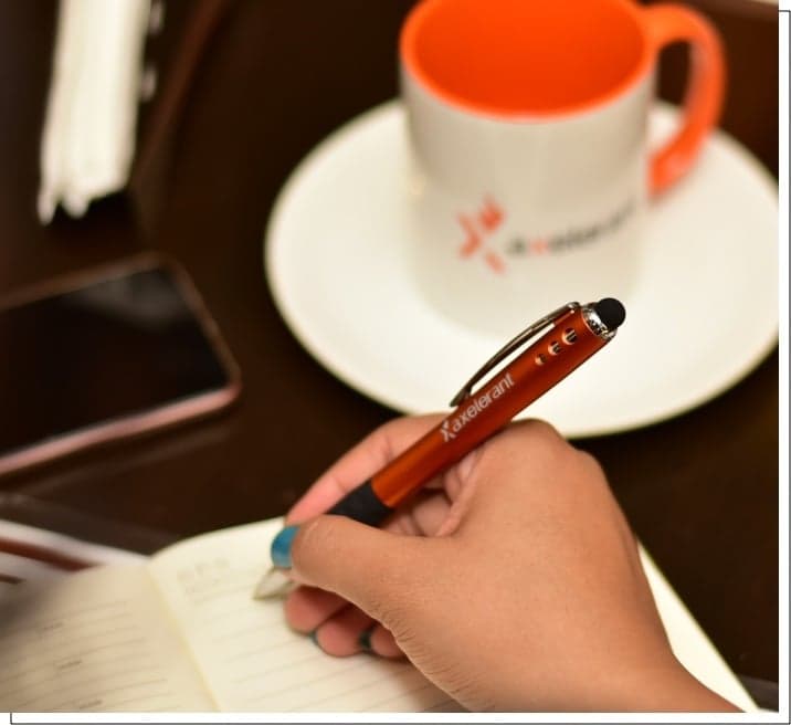 A notebook and Axelerant orange mug on a desk